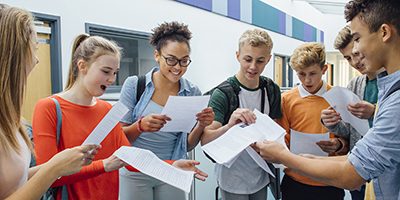 Happy students have received their exam results in high school. They are cheering and celebrating.