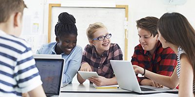 Group Of Teenage Students Collaborating On Project In IT Class